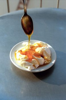 Honey flow down on yoghurt from spoon