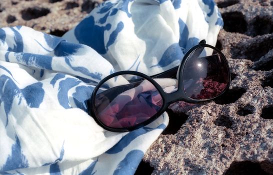 Sun glasses and cotton pareo on the stone