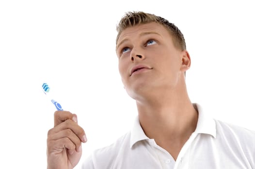 healthy male posing with toothbrush and looking upwards against white background