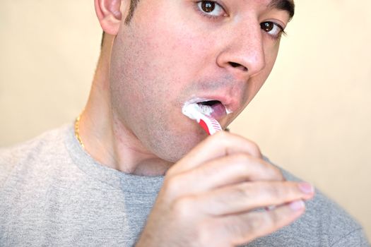 A closeup of a young man while he is brushing his teeth.