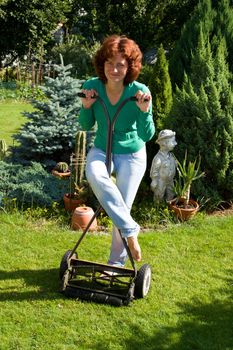 Girl with lawn mower in her garden