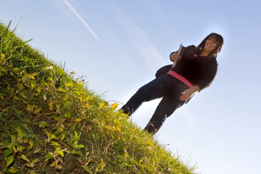 A young female student posing on a grassy hill on the school campus  