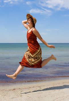 Girl in hat running along snad sea beach