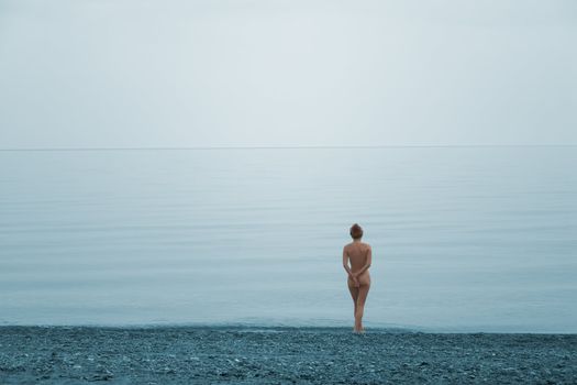 Lonely naked girl on the beach of quite sea