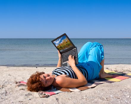 Girl working on laptop computer at sea beach