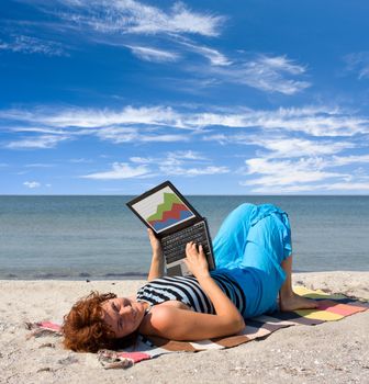 Girl working on laptop computer at sea beach