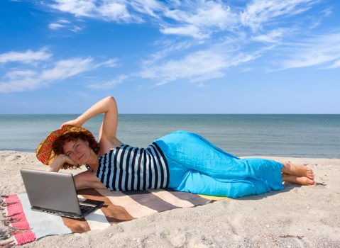 Girl working on laptop computer at sea coast