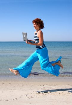 Girl with laptop running along sea beach