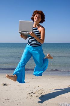 Girl with laptop computer running at sea coast