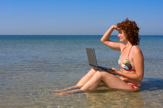 Girl with laptop computer sitting in the sea