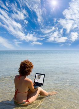 girl sitting in the sea and working on laptop computer