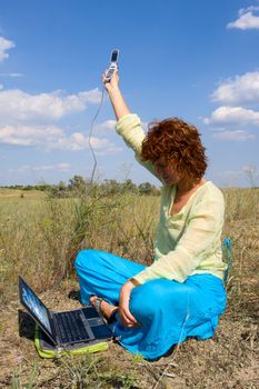 Girl with laptop try to connect internet by handy phone