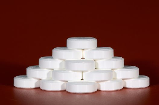 Piramid made from white tablets on red background