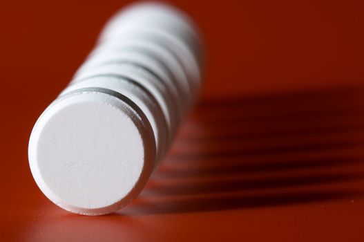 Column of tablets with shadow on red background