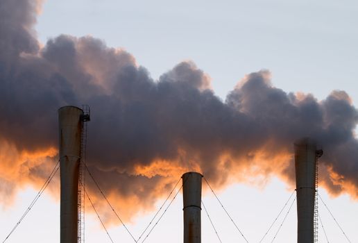 Factory pipes throwing out clouds of orange smoke