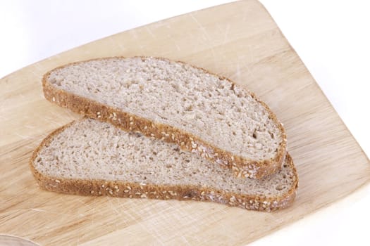 two slices of brown bread lying on a wood board isolated on a white background