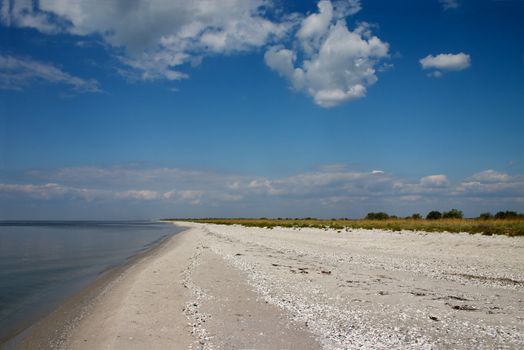 Lonely seaside with calm sea and blue sky with white clouds