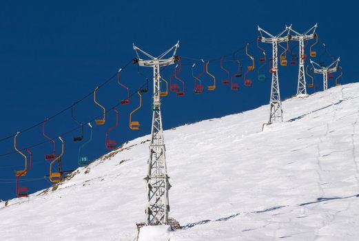 chair lift in blue sky under snow covered slope