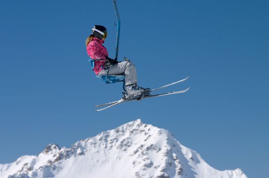 skier girl on ski lift under mountain