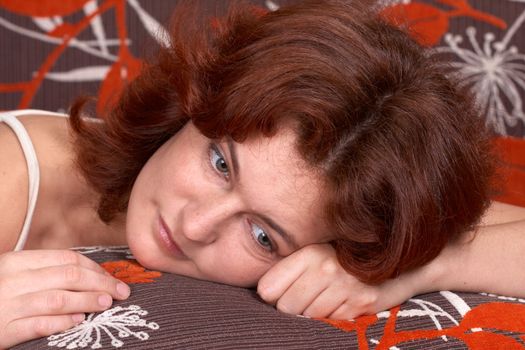 redheaded girl lying on orange sofe and dreaming