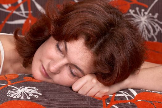 A beautiful red-haired woman taking a nap on her bed.