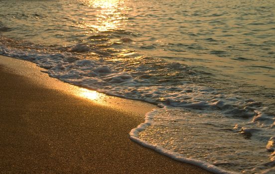 Sunset and sea surf on sand beach