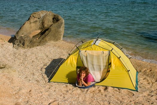 Woman lying in tent at sand sea beach and lookin up