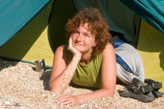 Girl lie in sand near of her tent