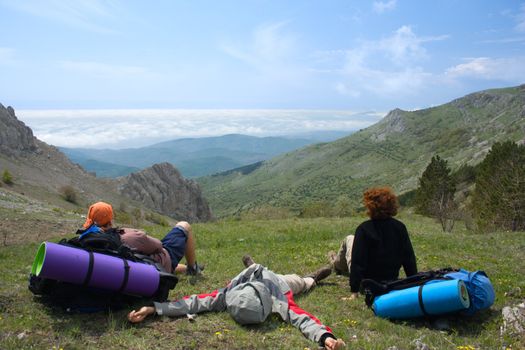 Backpackers relaxing on pass and looking to clouds