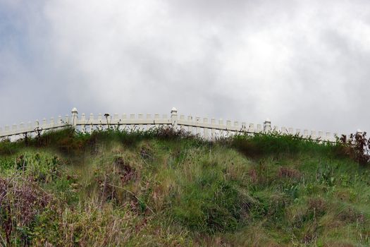 a white picket fence on a grassy hill