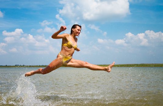 teen girl in bikini jumping high above the lake