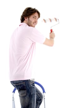 man standing on chair and holding paint roller on an isolated white background