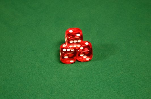 Three red dices on the green casino table