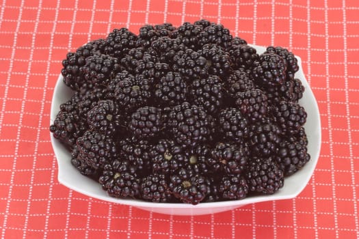 Fresh blackberries in a basket on red background