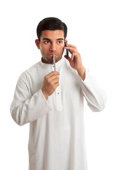 Worried troubled thinking mixed race ethnic man on a telephone call.  He is dressed in middle eastern south asian clothing  robe, thobe, kurta.   White background.