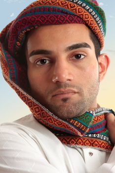 Arab man wearing a colourful wovan keffiyeh or turban style  head piece.  These headdresses serve a purpose of protecting nose and mouth from dust and sand storms as the fabric can be wrapped across the face when needed.