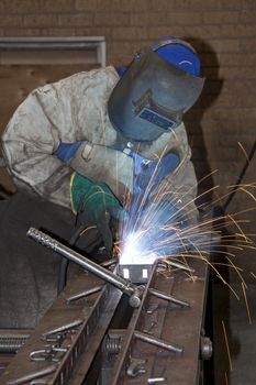 Factory Worker Welding metal on a production line