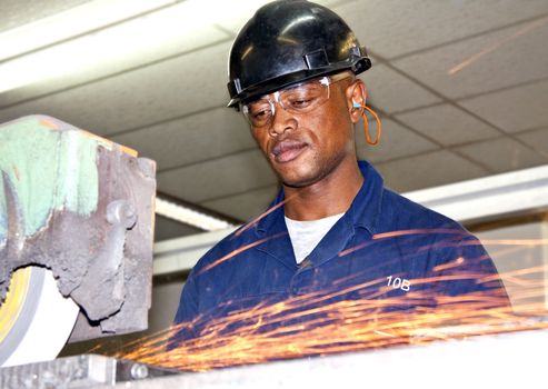 A man grinding a piece of metal in a factory