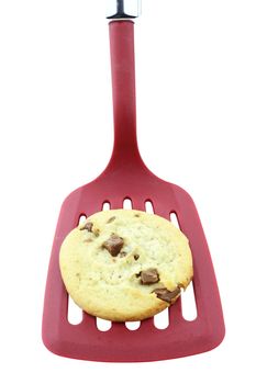 Chocolate chip cookie over a red spatulla isolated on white. Clipping path included.