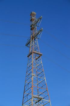 Top of the electricity pylon over blue sky.
