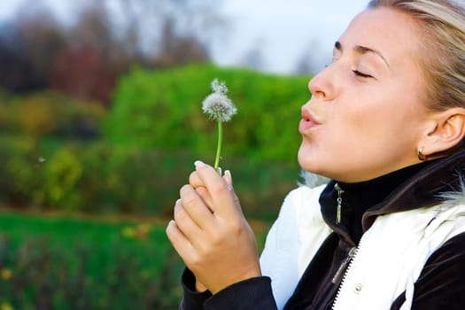Young girl and dandelion in the countryside