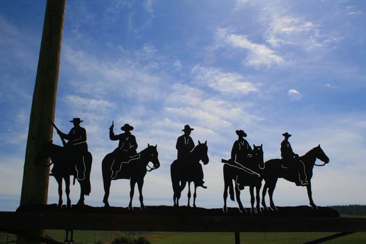 Five cowboys metal figurines over blue sky.

