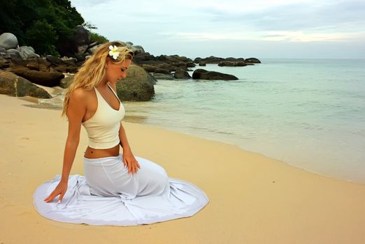Girl sitting on the sand beach and looking sad