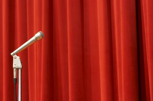 a crome microphone on a stage in front of a red curtain