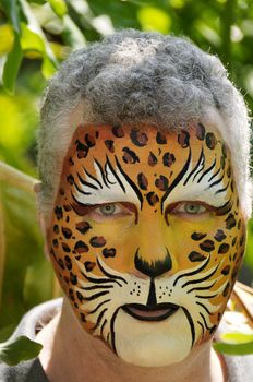 A man with his face painted like a leopard.