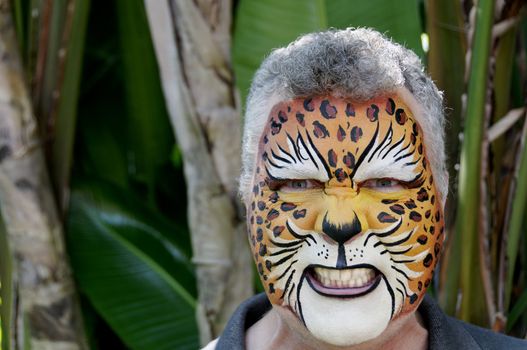 A man with his face painted to look like a leopard, growling.