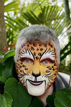 A smiling man with his face painted to look like a leopard.