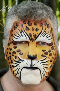 A man with his face painted like a leopard looking mean.