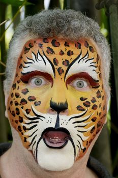 A man with his face painted like a leopard looking surprised.