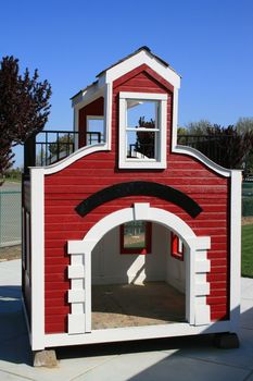 Red and white playhouse on a playground.
